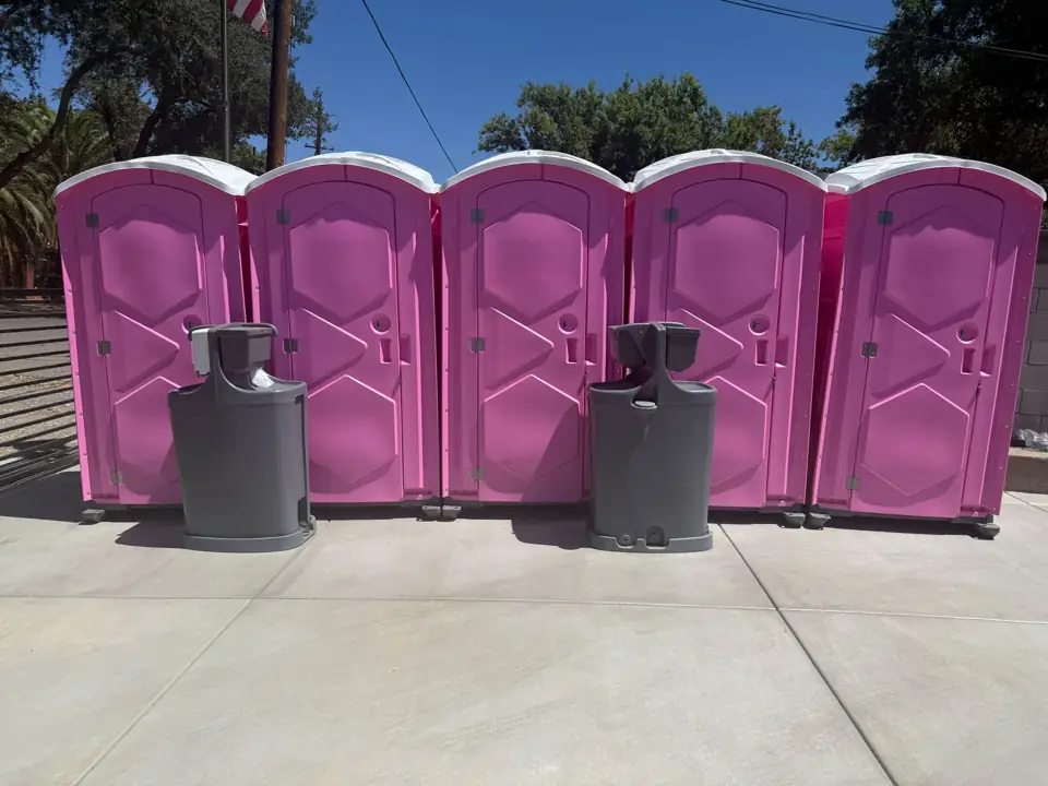 Row of event portable toilets with two hand-wash stations on concrete
