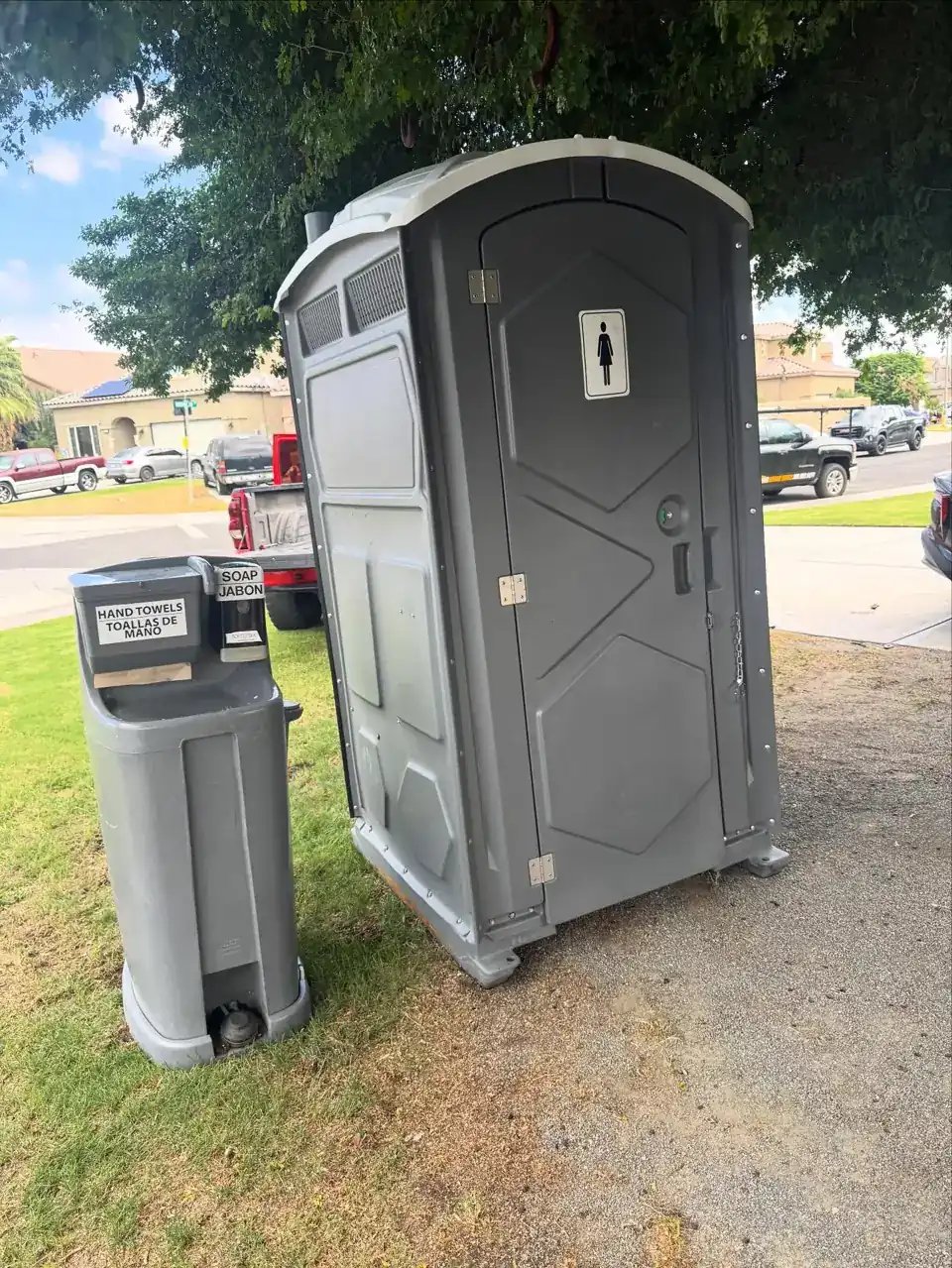 Standard portable toilet with a two-station hand-wash sink set on level grass
