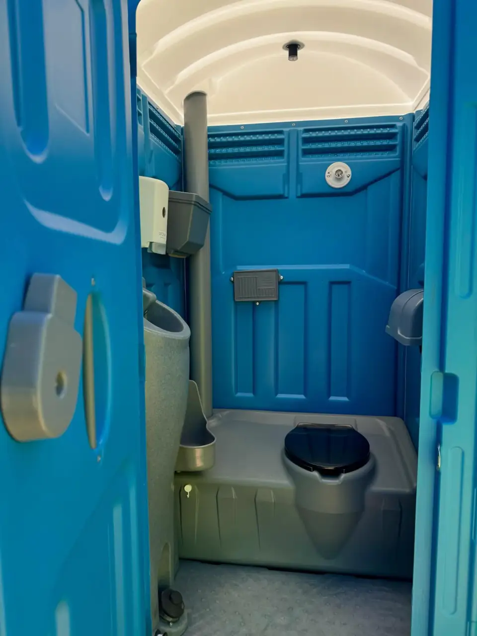 Standard portable toilet with the door open showing seat and urinal